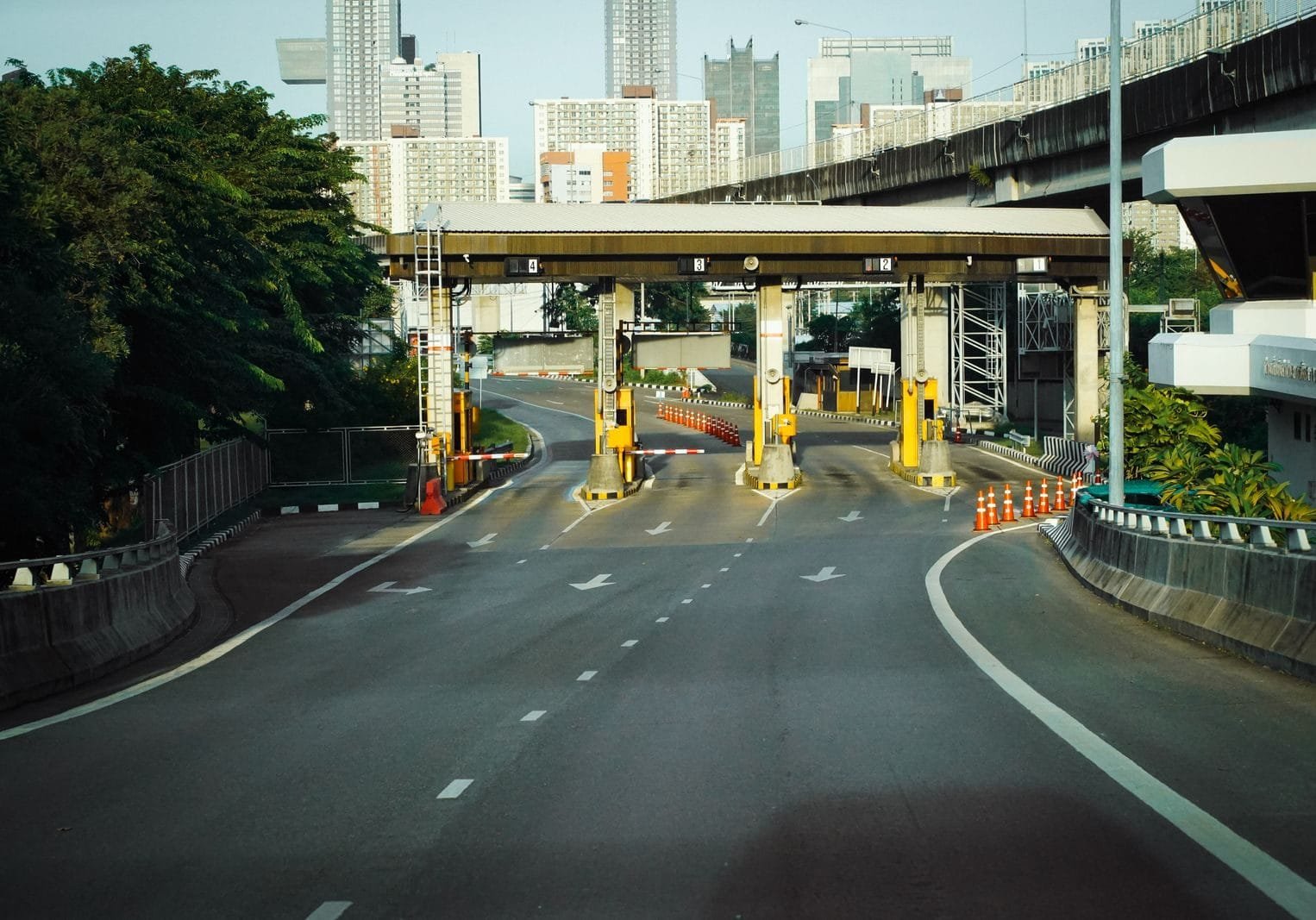 Pedágio de 50%: Como Funciona Essa Regra de Transição 1 Toll booth on a Bangkok highway with urban skyscrapers in the background, during a clear day.