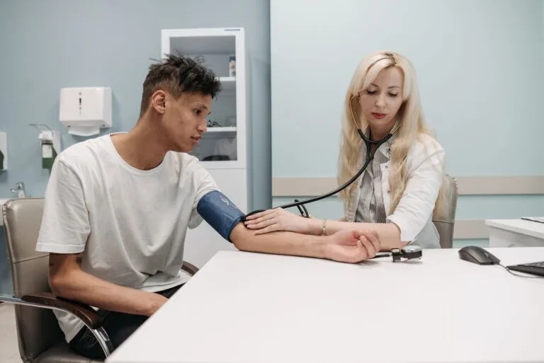 Perícia Médica INSS 2026: Guia Completo de Preparação 5 A doctor measures a patients blood pressure in a clinic setting, focusing on healthcare and wellness.