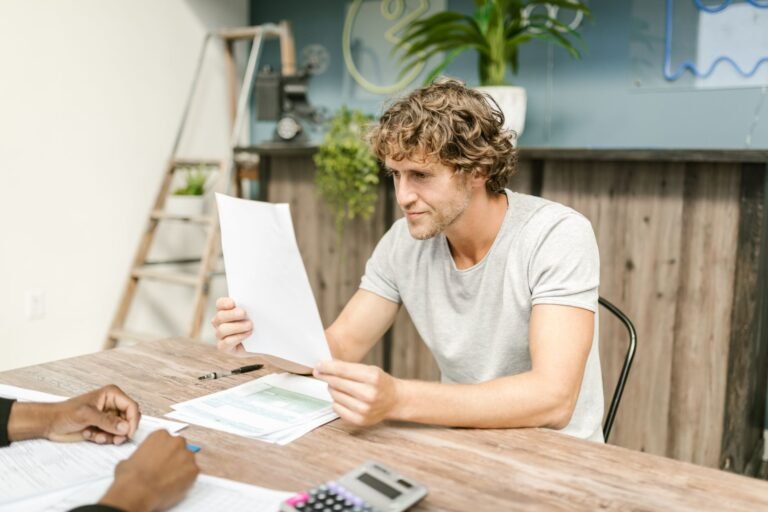 Periodo de graca: por quanto tempo o segurado continua protegido mesmo sem contribuir 5 A man with curly hair evaluates documents at a desk, highlighting focused work in a profes