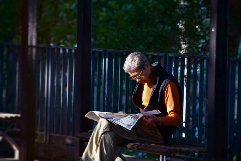 PF e CGU deflagram nova fase da Operação Sem Desconto e investigam descontos não autorizados em pensões e aposentadorias do INSS 6 man reading newspaper while sitting on bench in front of wooden fence