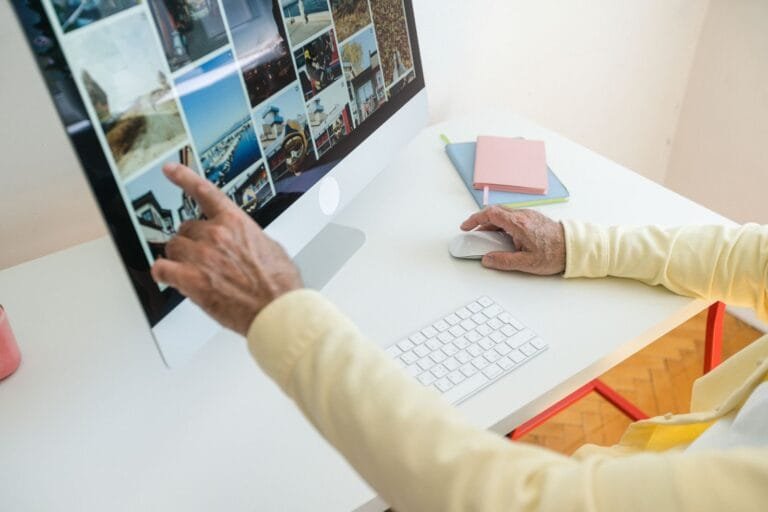 Plagio e uso de imagens de terceiros no seu site: como evitar processos 7 Senior adult browsing photos on a desktop computer in a modern indoor setting.