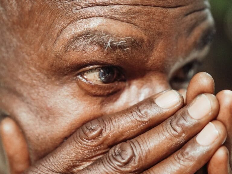 Como podemos ajudar? 13 Close-up view of a senior mans contemplative expression, highlighting wrinkles and aged hands.