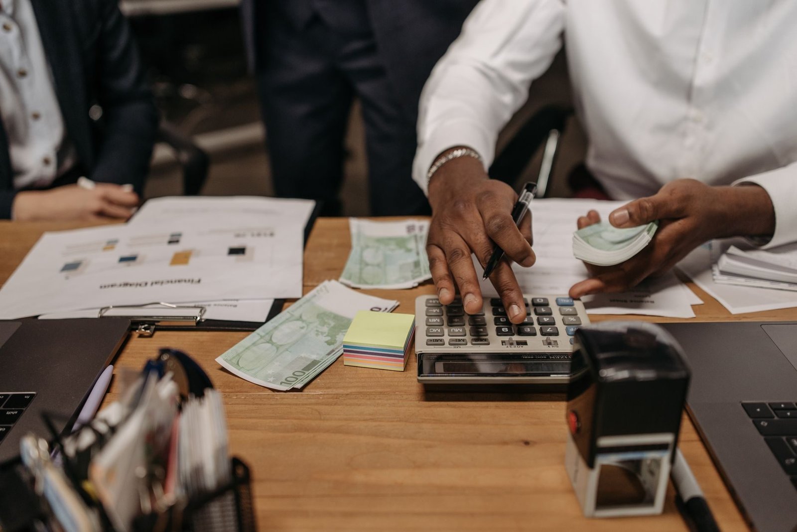 Planejamento sucessorio e tributario: organizar o patrimonio em vida 1 Professional setting with people handling cash and calculations using a calculator at a de