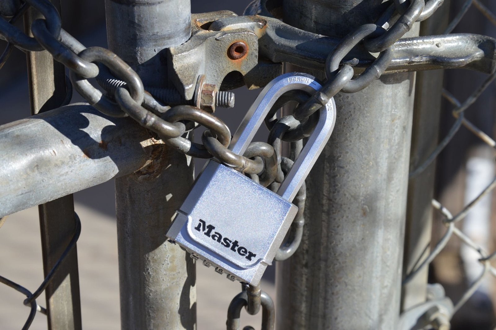 Detailed view of a padlock securing a metal gate with a chain, emphasizing safety and secu