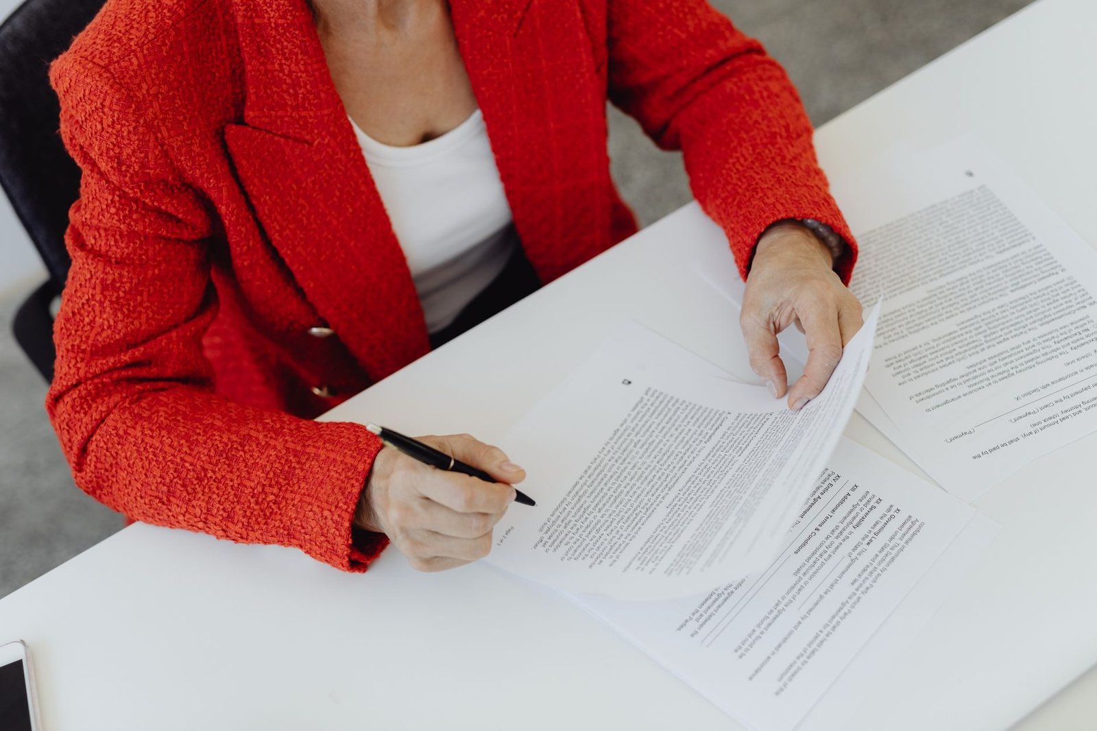 Portaria Conjunta MPS/INSS nº 13/2026 cria o Novo Atestmed e amplia o prazo da análise documental de 60 para até 90 dias 1 Woman in red blazer signs paperwork at a desk, emphasizing business responsibility.
