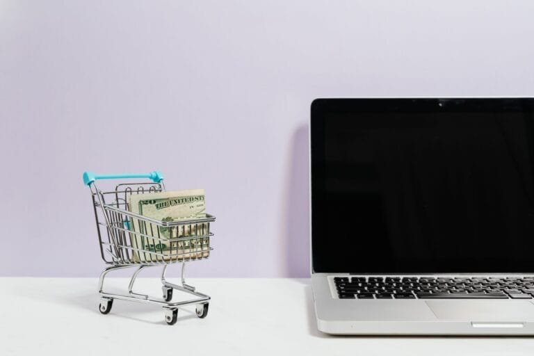 Carrinho de compras com dinheiro ao lado de um notebook, simbolizando direitos do consumidor em compras