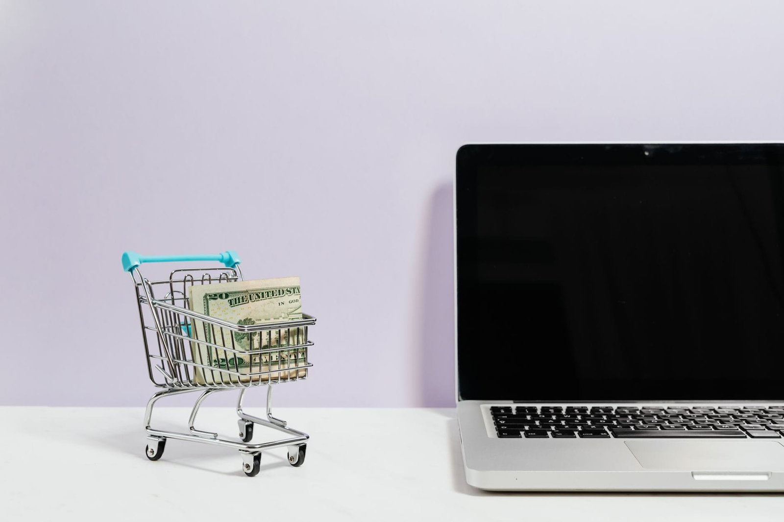 Carrinho de compras com dinheiro ao lado de um notebook, simbolizando direitos do consumidor em compras