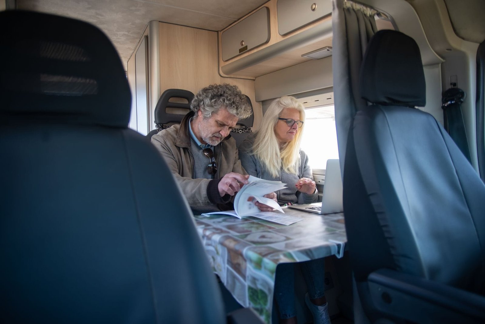 Progressão no plano de cargos do bancário e a média do benefício 1 An adult couple working indoors in a caravan, using a laptop and reviewing documents.