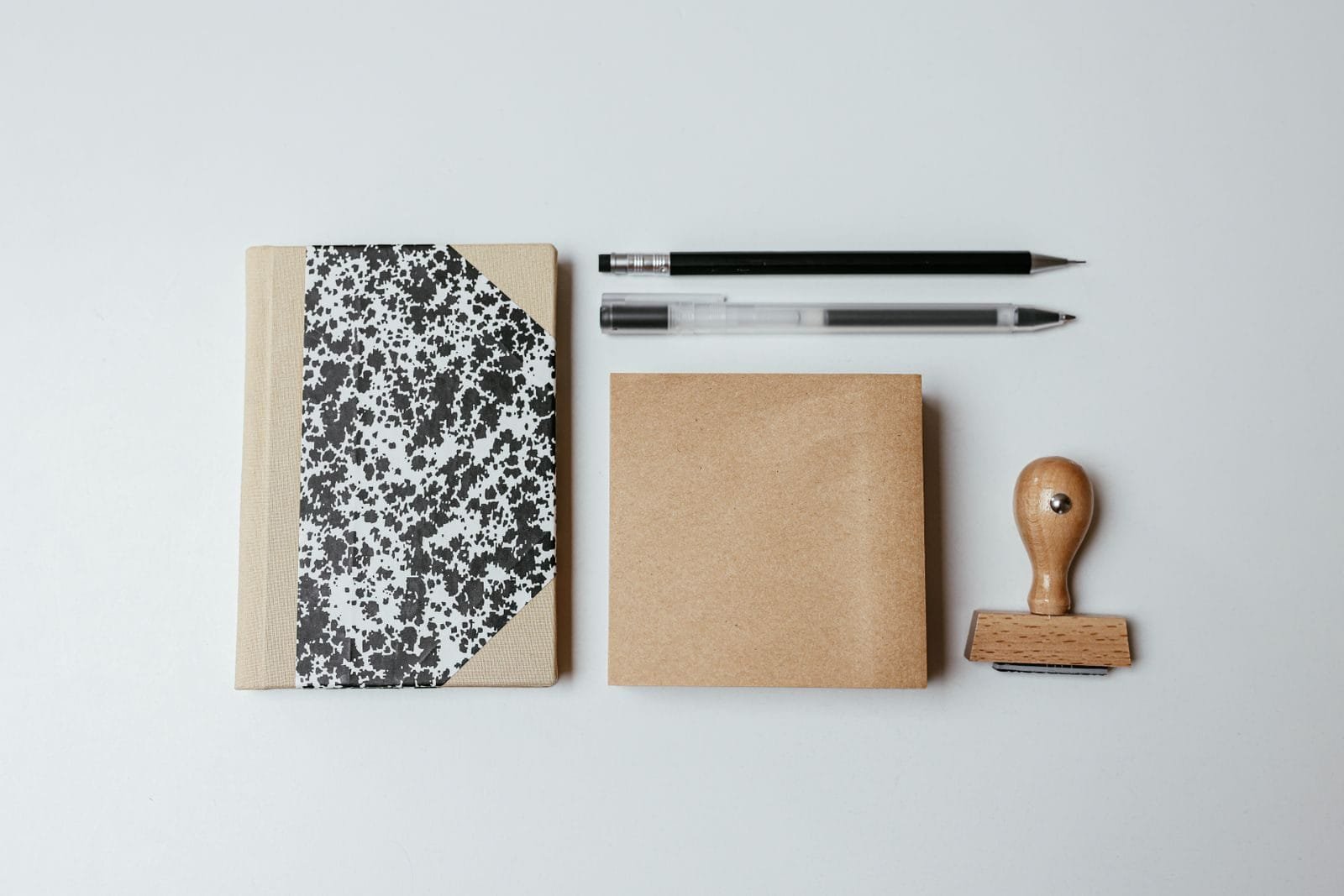 Propriedade Intelectual: Registro de Marca e Patente 1 A modern flatlay featuring a notepad, pens, and a wooden stamp on a clean background.