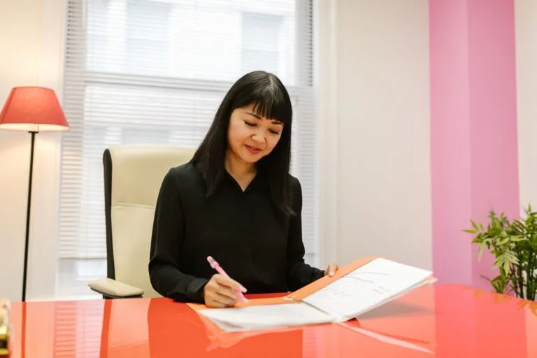 Quebra de caixa do bancário: a Súmula 247 do TST e o INSS 4 Asian woman working in a bright modern indoor office setting reviewing paperwork.
