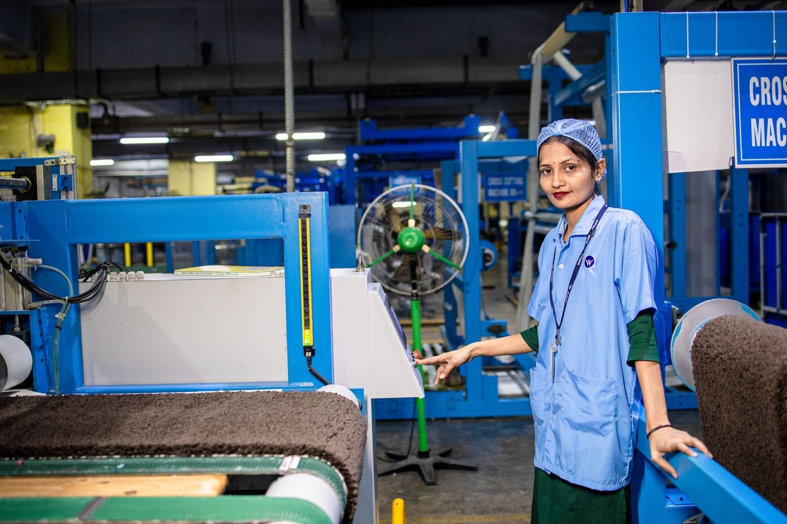 A female worker in a textile factory operating machinery with precision and focus.