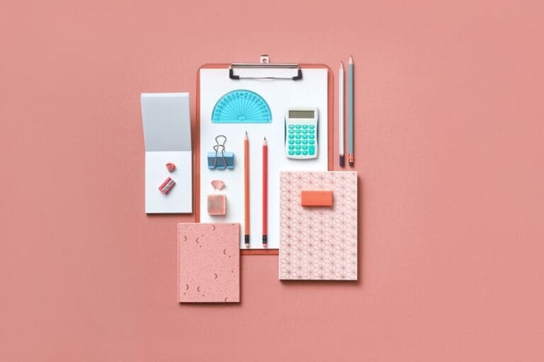 Collection of colorful stationery items arranged neatly on a pink background.