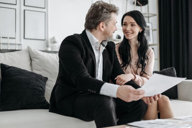 Regra de transicao por pontos: como funciona a soma de idade e tempo de contribuicao 8 Couple smiling while sitting on a couch reviewing documents indoors.
