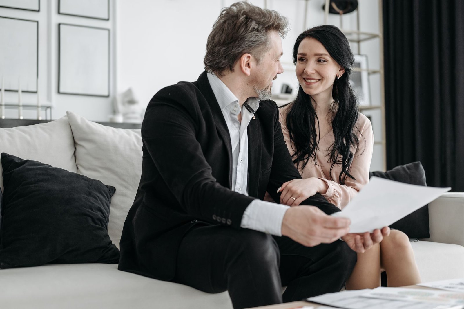 Regra de transicao por pontos: como funciona a soma de idade e tempo de contribuicao 1 Couple smiling while sitting on a couch reviewing documents indoors.