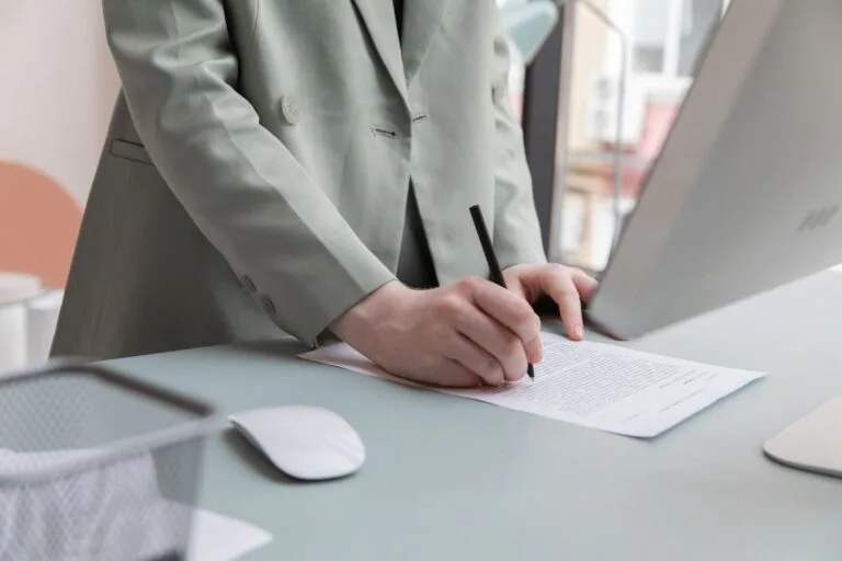 Rescisão Indireta: Quando o Empregado Pode 'Demitir' o 7 Unrecognizable worker standing at table with computer while taking notes in document while working in office