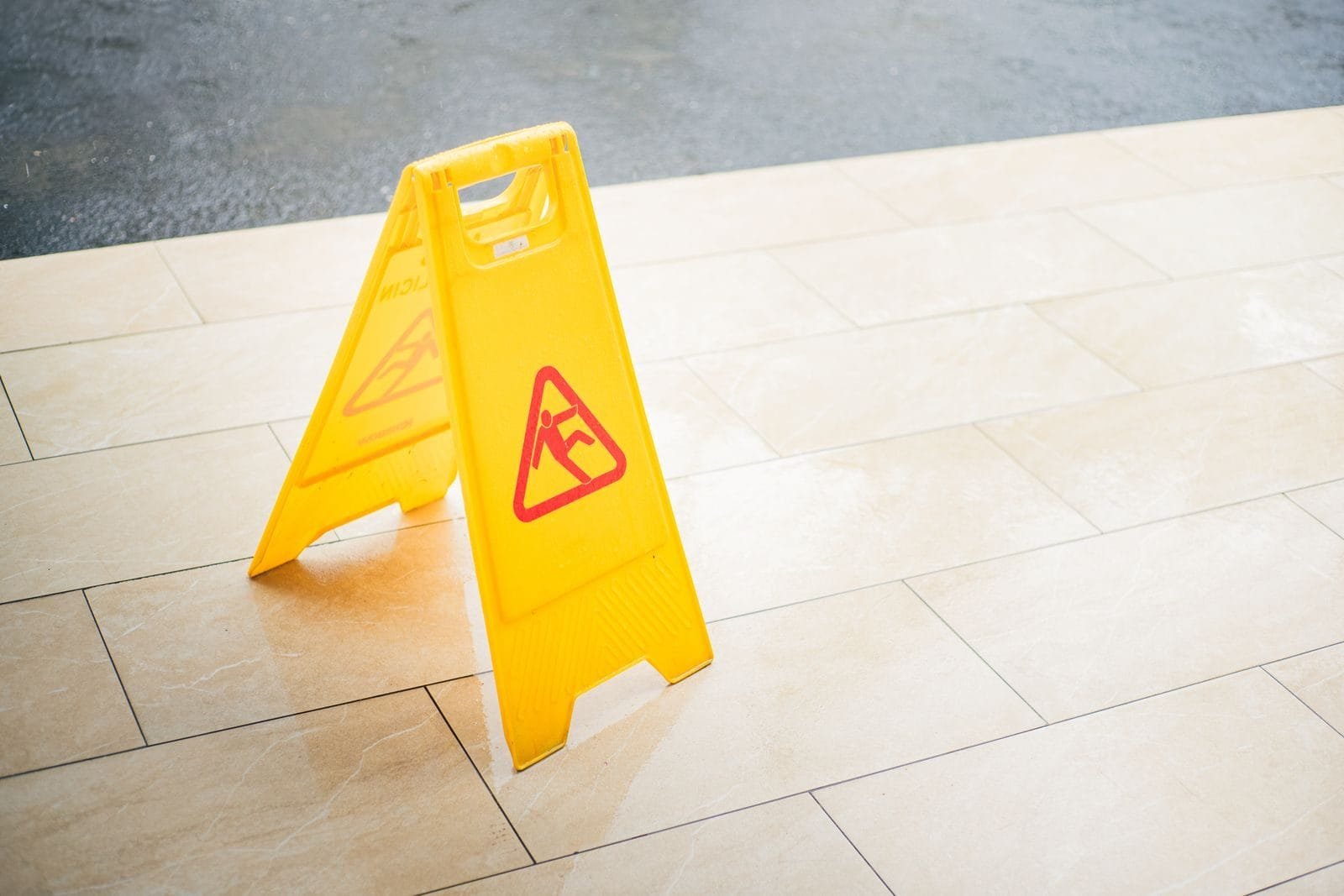 Responsabilidade civil: quando você é obrigado a indenizar outra pessoa 1 A bright yellow caution sign placed on a tile floor indicating a wet area for safety.