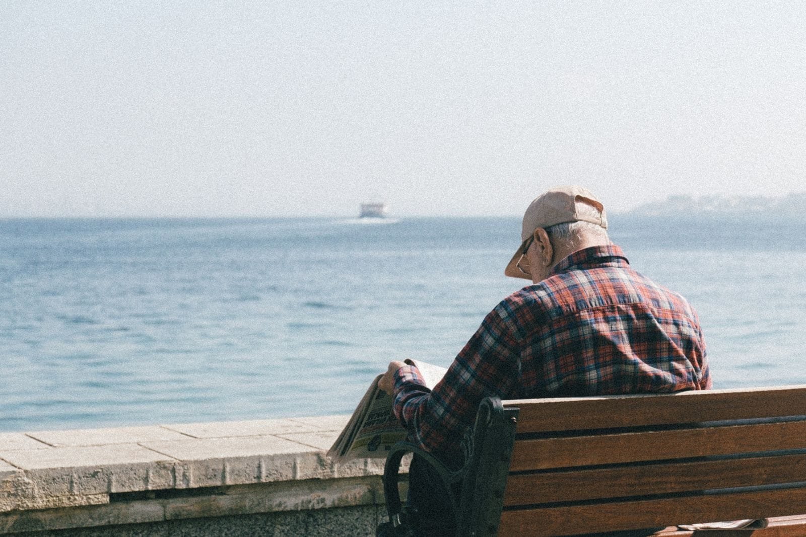 Revisão Buraco Negro: Quem Tem Direito e Como Funciona 1 Senior man enjoys reading a newspaper while sitting by the seaside, embracing relaxation.