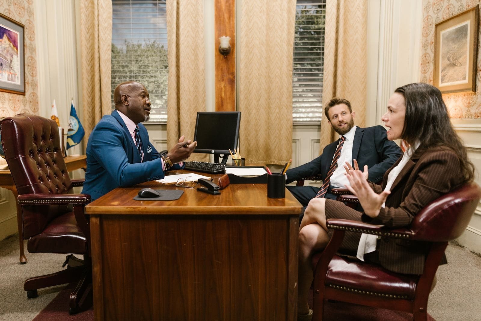 Segredo profissional do advogado: por que a confidencialidade protege o cliente 1 Three attorneys in a legal discussion at a well-appointed law office.