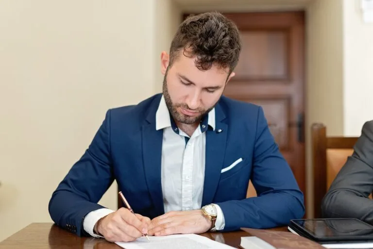 Servidor Temporário: Direitos, Limitações e Contratação 6 Confident businessman in a suit signing a contract at the office desk.