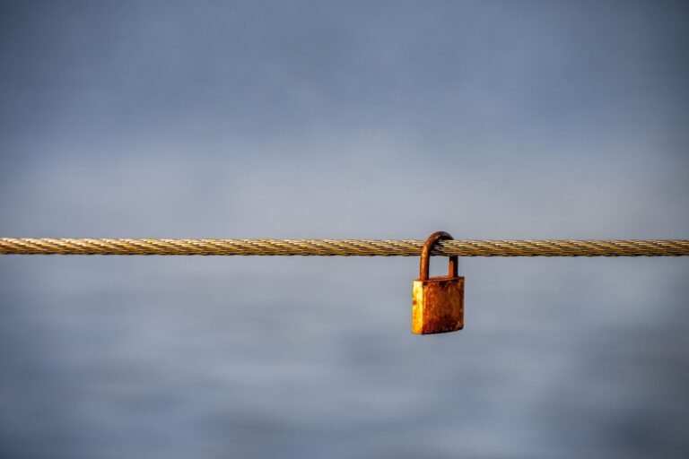 A rustic padlock secured to a sturdy cable set against a peaceful blue background. Ideal f