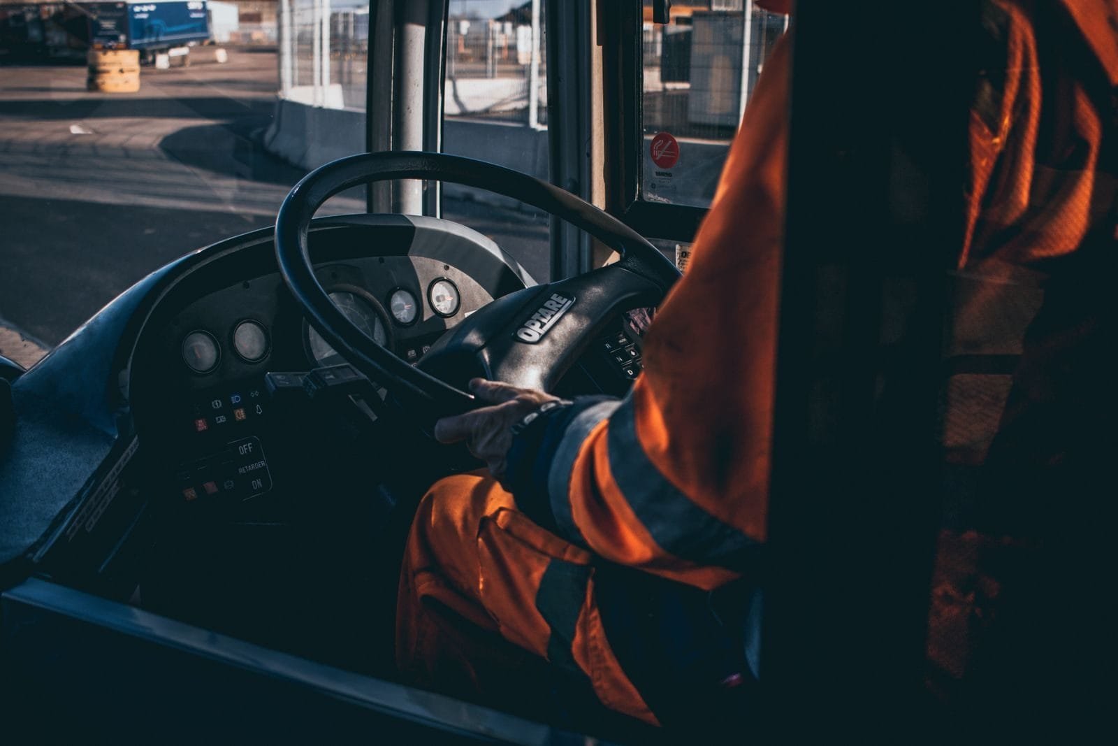 STJ admite o reconhecimento de aposentadoria especial por penosidade a motoristas e cobradores de ônibus e a motoristas de caminhão após a Lei 9.032/1995, desde que perícia individualizada comprove exposição habitual e permanente (Tema 1.307) 1 Bus driver operating vehicle from the cockpit in an industrial setting, showcasing control and focus.