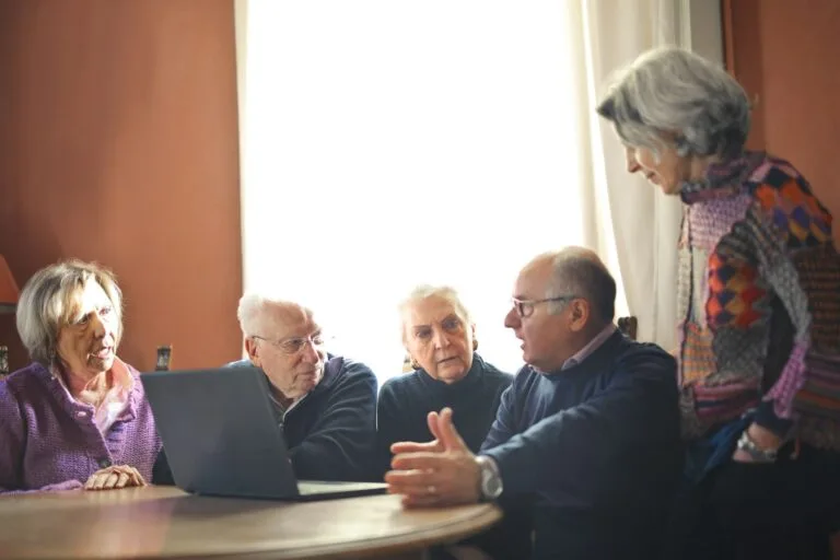 STJ dispensa, em repetitivo, a remessa necessária em ações previdenciárias cujo valor seja aferível por cálculo simples e fique abaixo do limite do art. 496, §3º, I, do CPC (Tema 1.081) 7 Group of senior adults discussing around a laptop in a warm indoor setting.