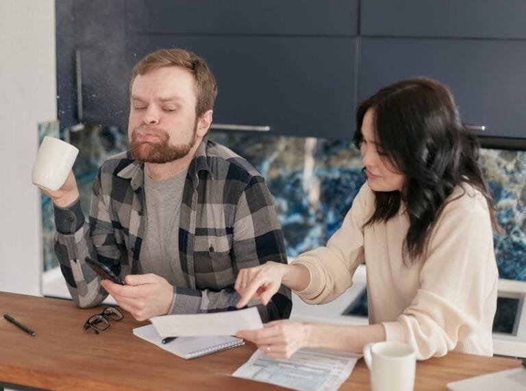 Superendividamento: como repactuar dívidas e preservar o mínimo existencial 7 A couple reviews bills at their kitchen table, looking concerned and thoughtful.