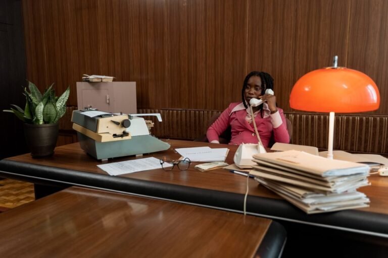 Tempo de contribuicao perdido: como recuperar periodos nao registrados 2 A woman in a retro office setting making a phone call with vintage decor and a typewriter.