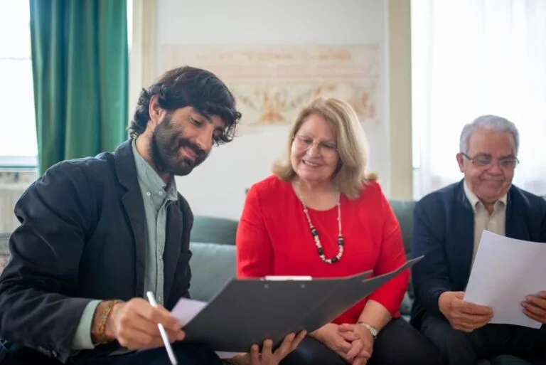 A consultant assists senior clients in a modern setting, signing documents together.