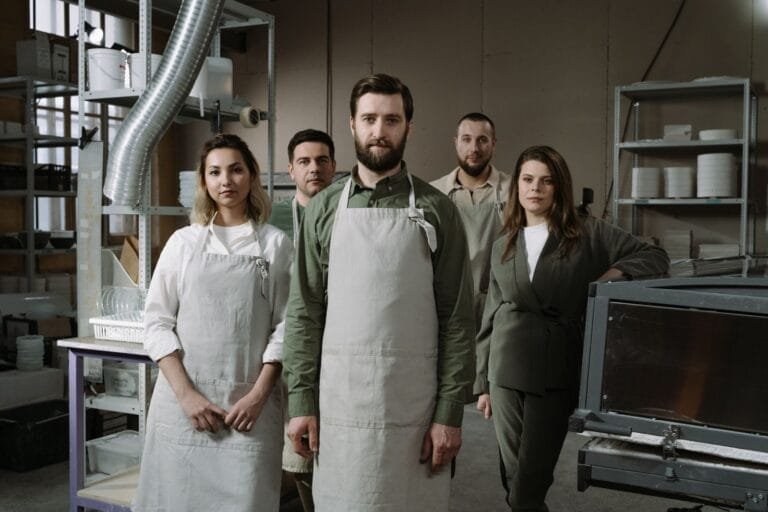 Group of professionals in aprons standing in an industrial workshop, showcasing teamwork.