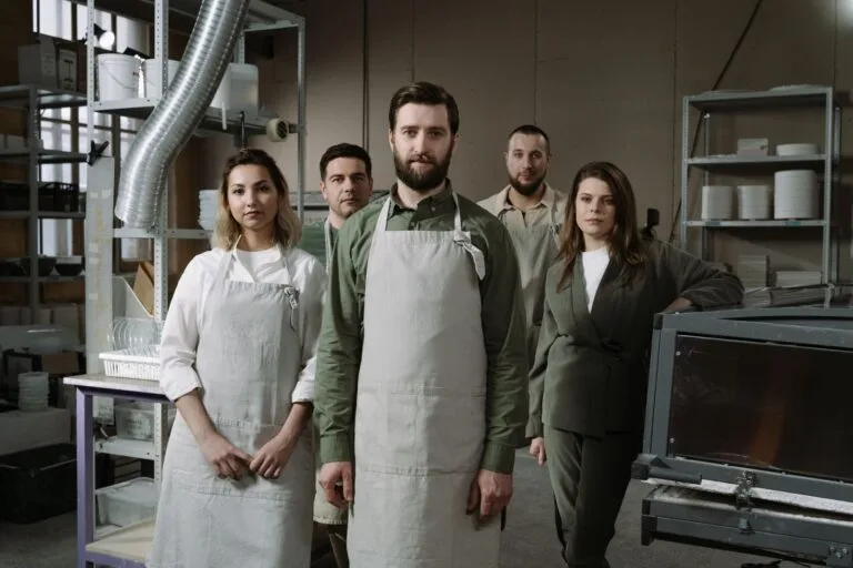 Group of professionals in aprons standing in an industrial workshop, showcasing teamwork.