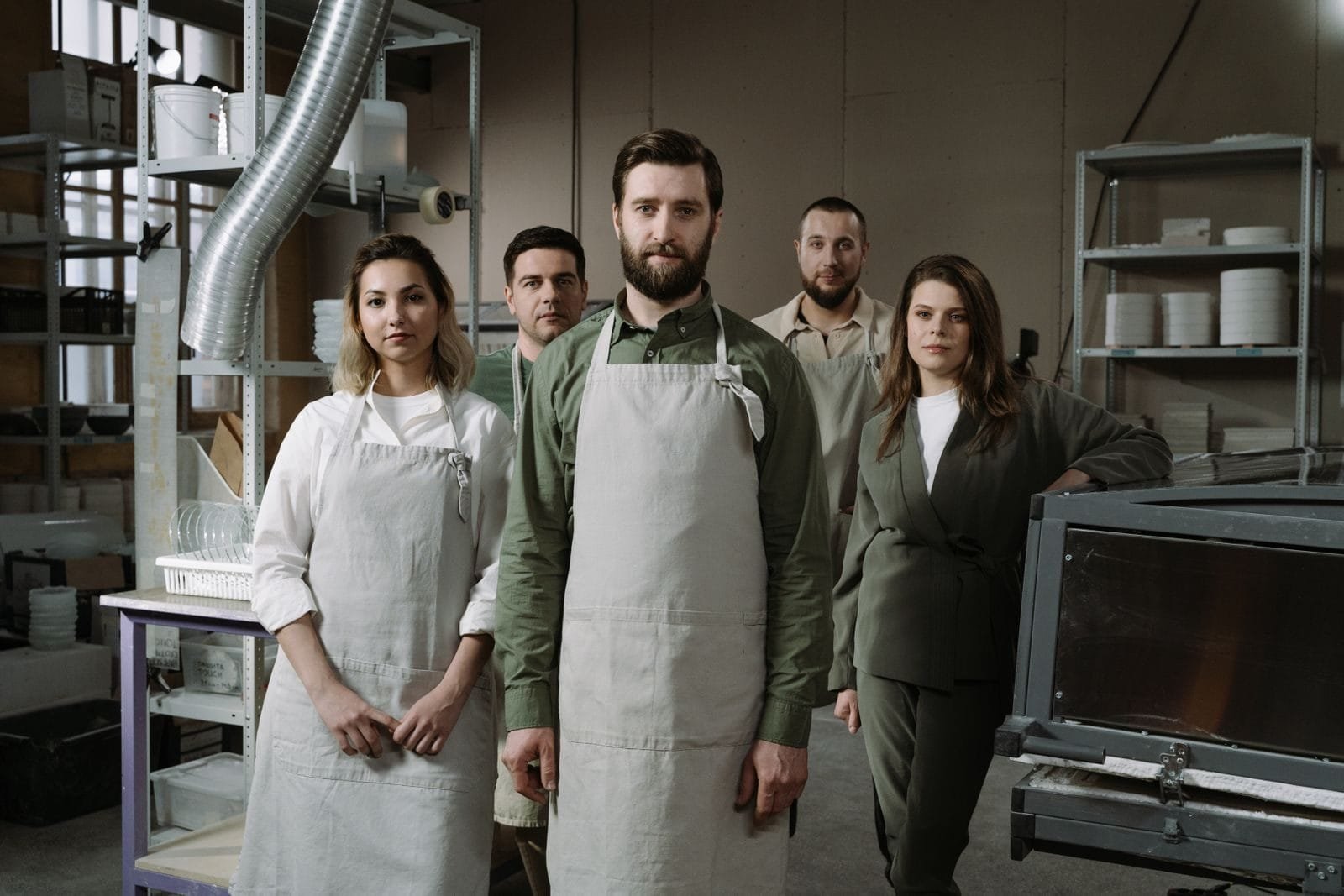 Group of professionals in aprons standing in an industrial workshop, showcasing teamwork.