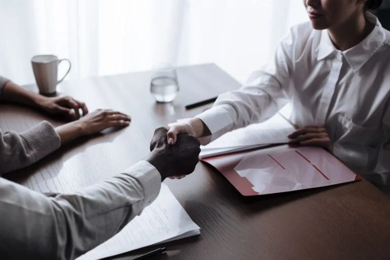 Tipos Societários MEI, EI, LTDA, SA: Qual Escolher 2 Professional handshake between diverse individuals over a business contract indoors.