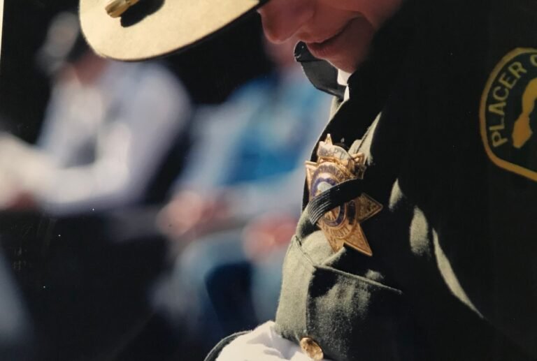 A focused shot of a police officer wearing a uniform and badge outdoors with shallow depth of field.