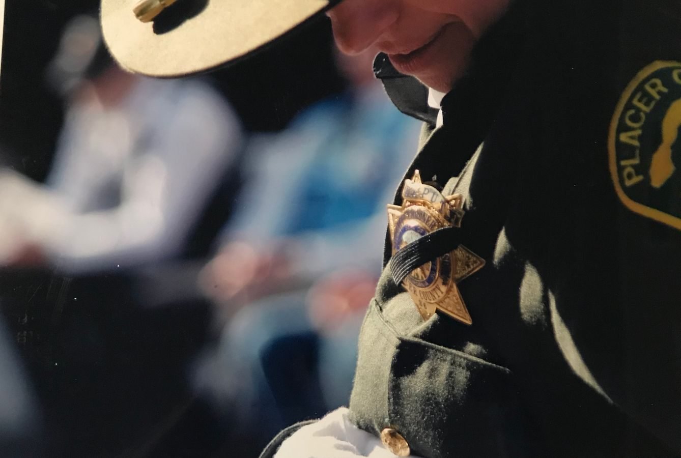 A focused shot of a police officer wearing a uniform and badge outdoors with shallow depth of field.