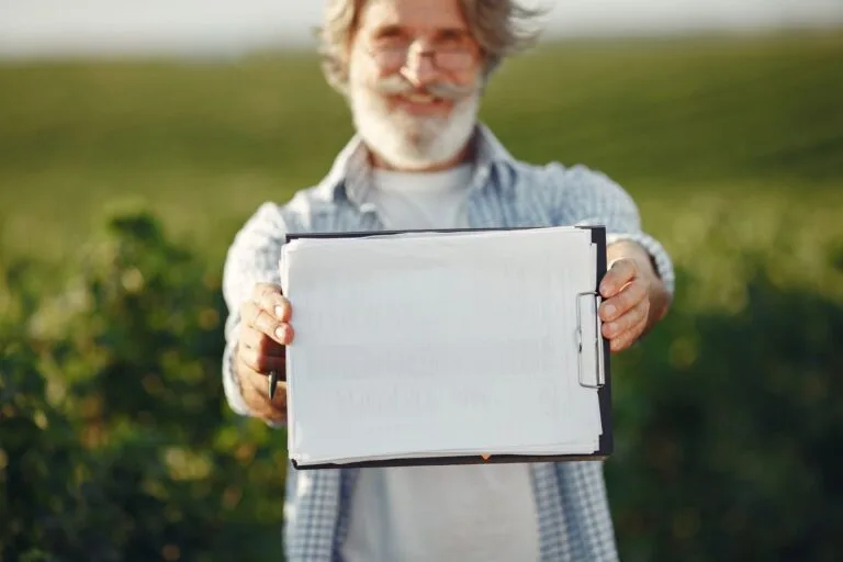 TNU reconhece certidão eleitoral com profissão rural e declaração de sindicato (mesmo sem homologação do INSS) como início de prova material de segurado especial rural 7 Bearded senior man with glasses holding a clipboard in a green field on a sunny day.