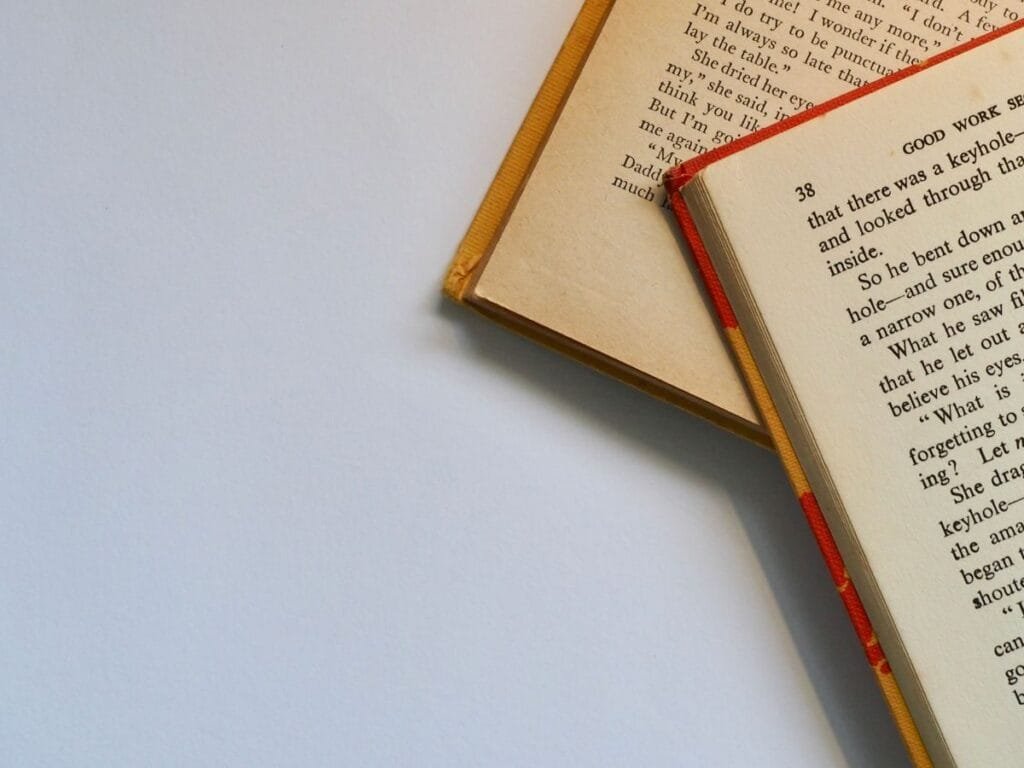 Top view of open books with visible pages and text on a clean white background.