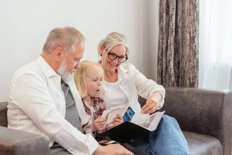 Grandparents and granddaughter cherish family memories while looking through a photo album