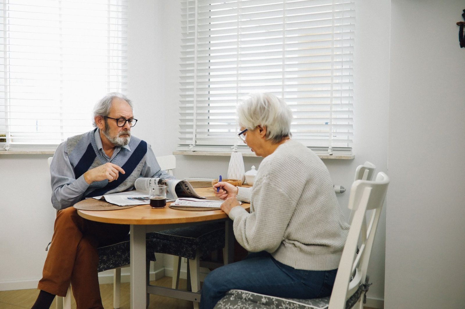 Transicao por idade minima progressiva: entenda o avanco gradual da idade exigida 1 Elderly couple reading newspapers and having coffee together in a bright dining room.