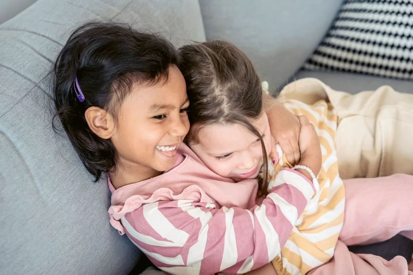 Pensão por morte: quem são os dependentes e a ordem de prioridade 1 High angle of happy adorable best friends cuddling each other while sitting on comfortable sofa at home