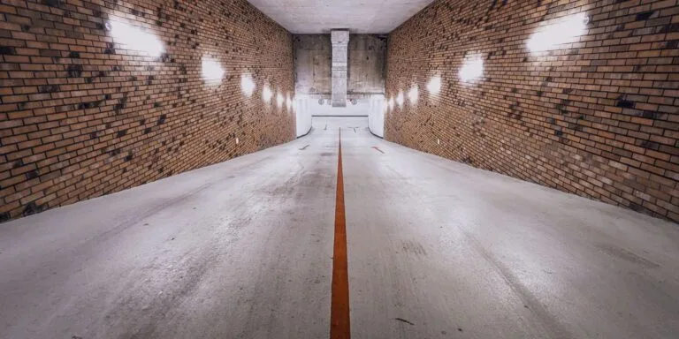 Vaga de garagem e uso de áreas comuns: conflitos frequentes em condomínio 4 An underground brick-walled ramp with dim lighting and a single yellow line, creating a cinematic feel.