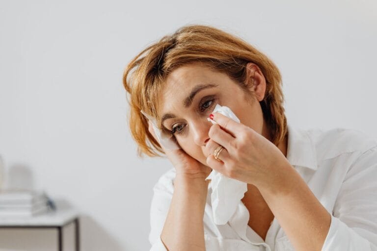 Vazou foto intima sem consentimento: o que a vitima pode fazer agora 4 Portrait of woman holding tissue, expressing emotion, wiping tears.