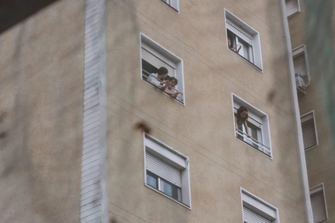 Vizinho Barulhento: Medidas Legais que Você Pode Tomar 1 People looking out from windows in a city apartment building showing urban life.