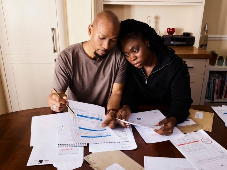 A couple sitting at a table reviewing financial documents, highlighting domestic budgeting