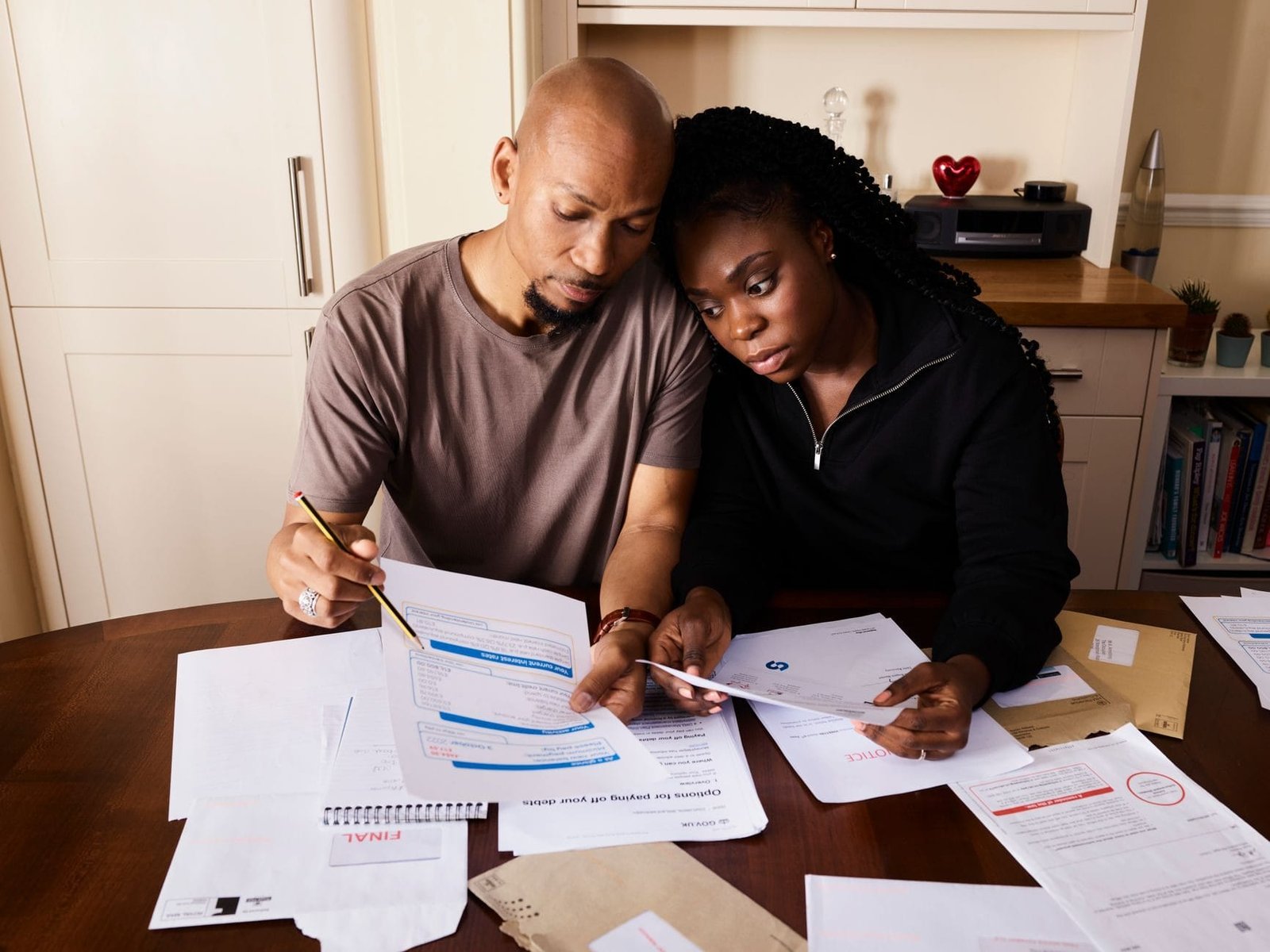 A couple sitting at a table reviewing financial documents, highlighting domestic budgeting