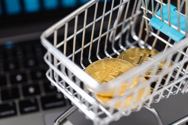 Close-up of bitcoins in a shopping cart placed on a laptop, symbolizing digital currency t