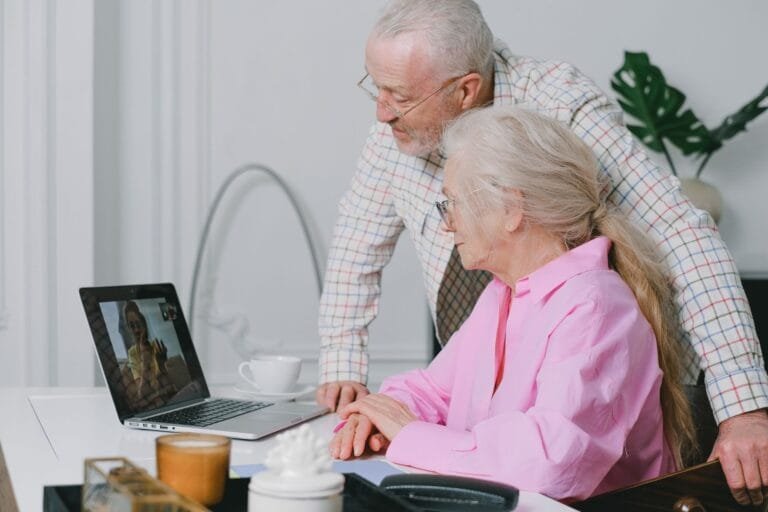 Elderly couple enjoying a video call on their laptop at home, showcasing family connection