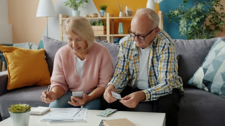 Elderly couple reviews finances at home on couch