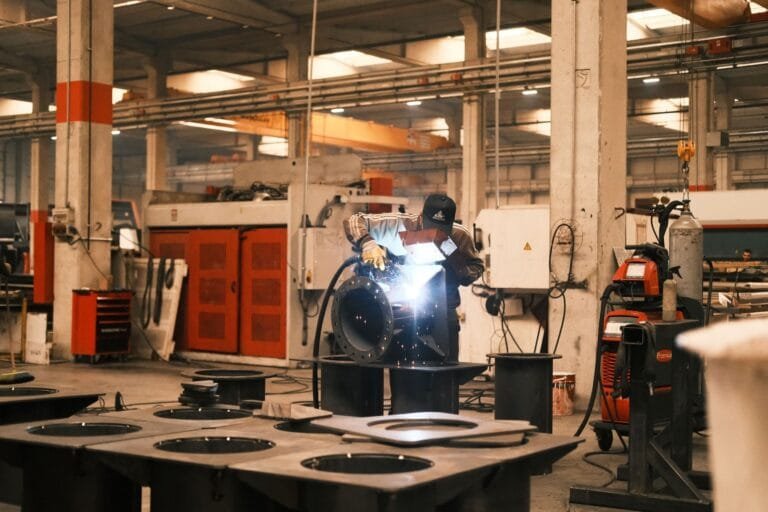 Trabalhador com equipamentos de proteção executa soldagem industrial