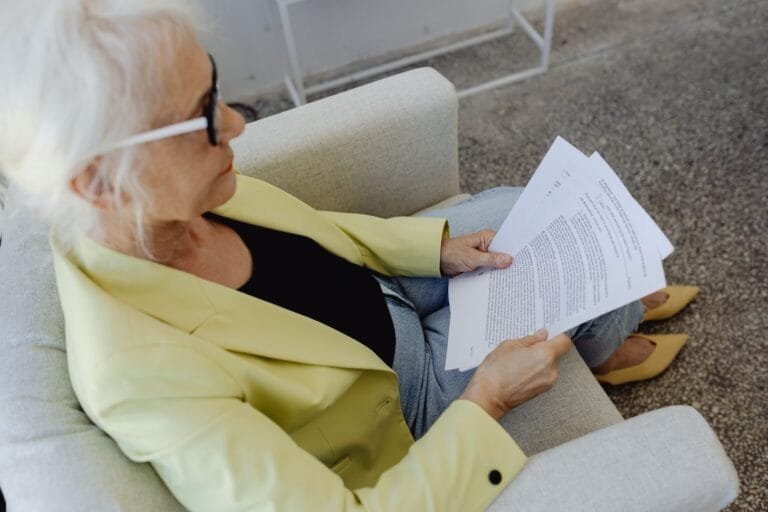 Mulher idosa lê documentos sentada
